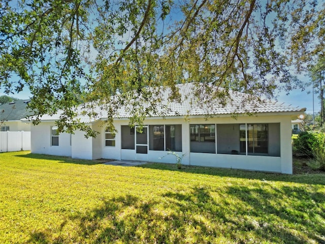 rear view of property featuring a lawn and fence