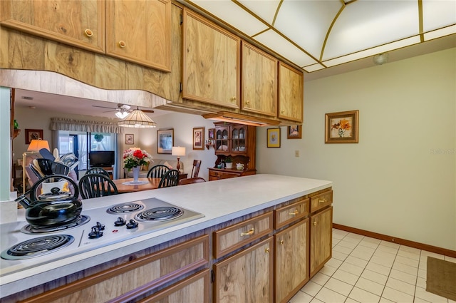 kitchen with baseboards, electric cooktop, light countertops, and light tile patterned flooring