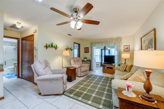 living room with a ceiling fan, visible vents, a textured ceiling, and light tile patterned floors