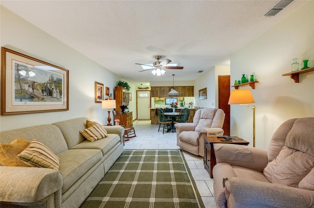 living room with light tile patterned floors, a textured ceiling, and a ceiling fan