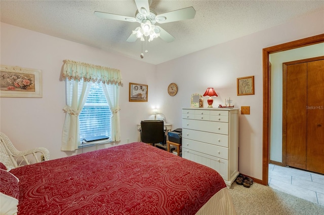 bedroom with light tile patterned floors, light carpet, ceiling fan, a textured ceiling, and baseboards