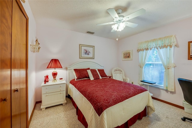 bedroom featuring visible vents, light carpet, ceiling fan, a textured ceiling, and baseboards