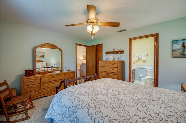 carpeted bedroom with a textured ceiling, ceiling fan, ensuite bathroom, visible vents, and a closet