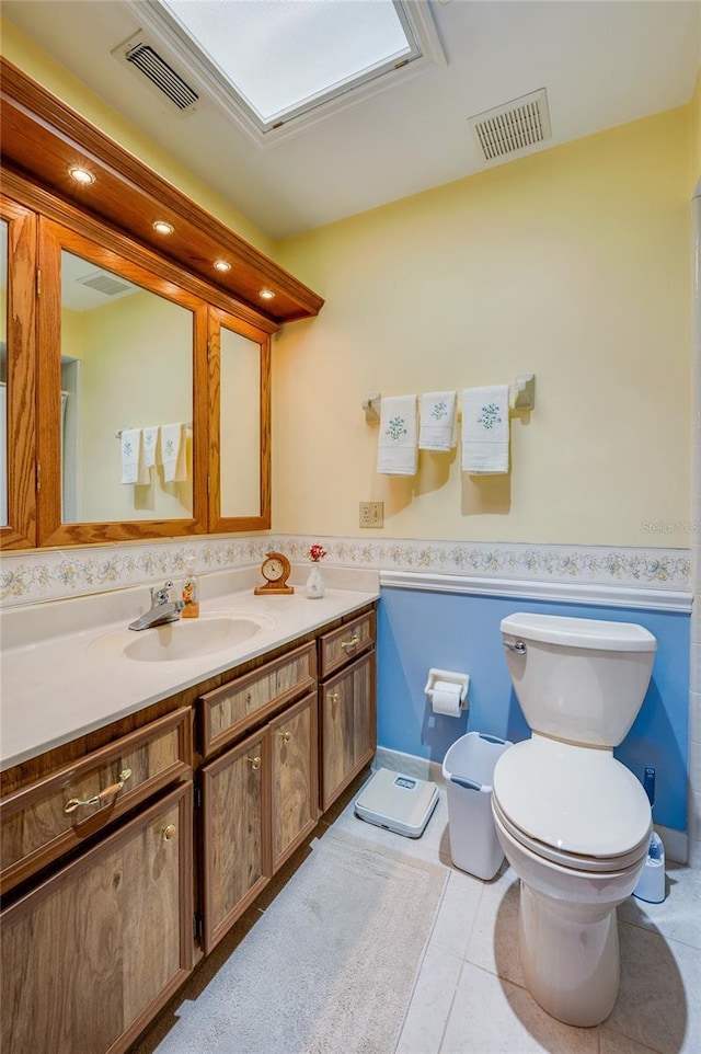 bathroom with a wainscoted wall, visible vents, and toilet