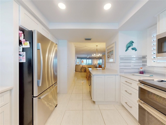 kitchen featuring light tile patterned floors, a notable chandelier, stainless steel appliances, white cabinetry, and light countertops