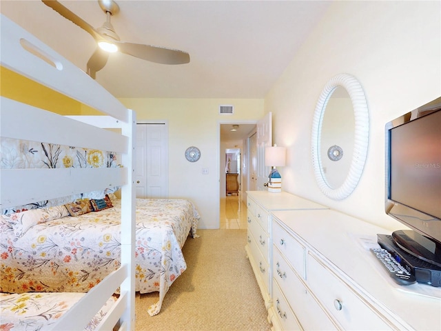 bedroom with a closet, visible vents, ceiling fan, and light carpet