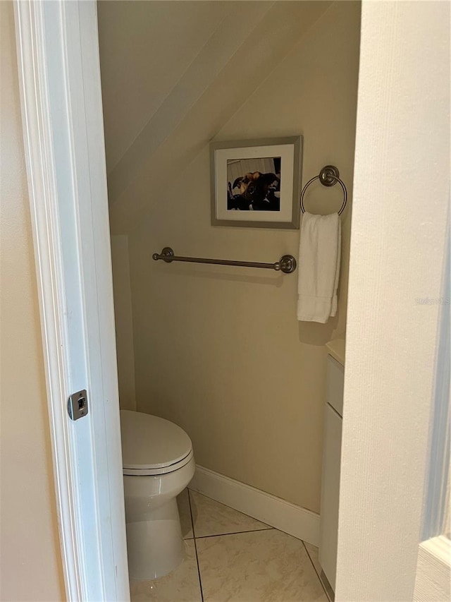 bathroom featuring toilet, tile patterned flooring, baseboards, and vaulted ceiling