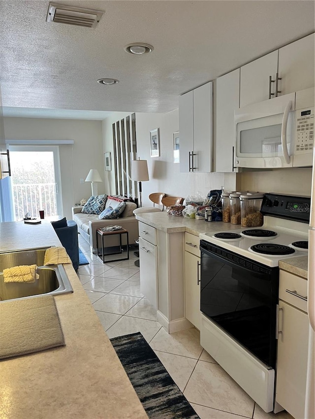 kitchen with white microwave, visible vents, range with electric cooktop, and light countertops