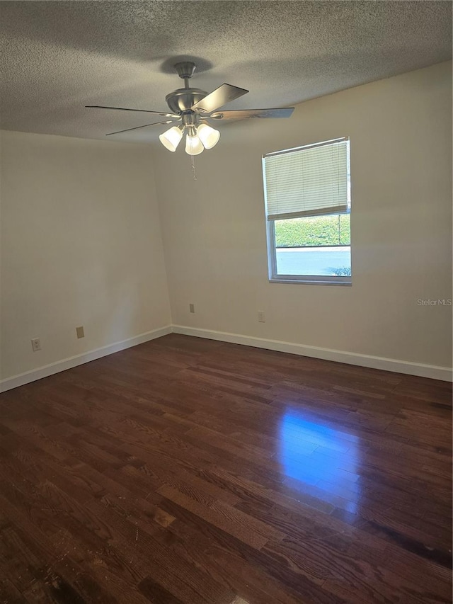 spare room with ceiling fan, a textured ceiling, dark wood finished floors, and baseboards