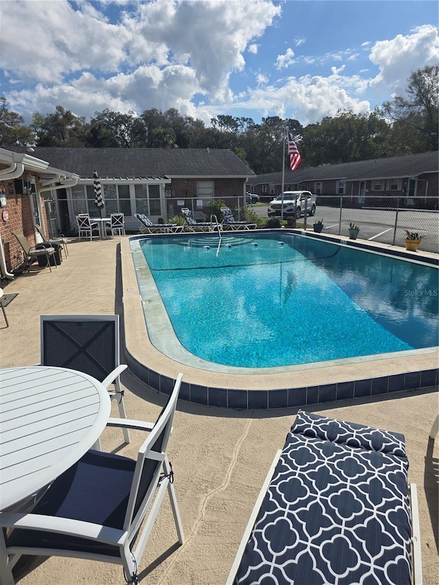 community pool featuring outdoor dining space, fence, and a patio