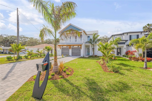 view of front of property featuring a garage, a balcony, a standing seam roof, decorative driveway, and a front yard