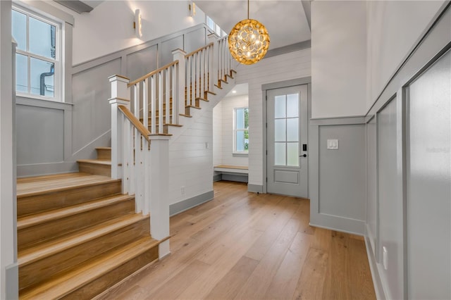 foyer featuring stairs, light wood-type flooring, a wealth of natural light, and a decorative wall