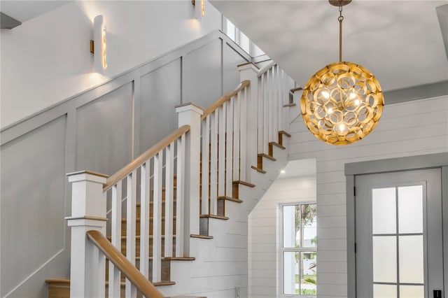 stairs featuring a notable chandelier and a decorative wall