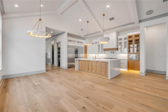 kitchen with tasteful backsplash, visible vents, light wood-style flooring, light countertops, and beam ceiling