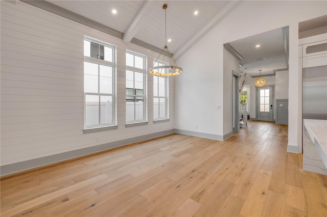 unfurnished dining area featuring baseboards, an inviting chandelier, light wood-type flooring, high vaulted ceiling, and beam ceiling