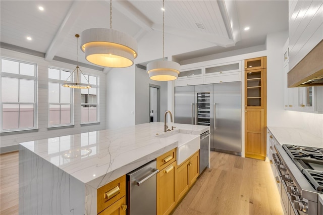 kitchen with high end appliances, lofted ceiling with beams, a spacious island, light wood-type flooring, and a sink