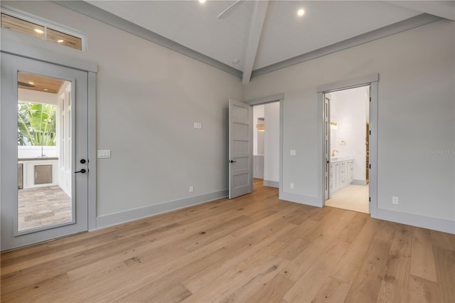 spare room with light wood-style flooring, baseboards, and vaulted ceiling