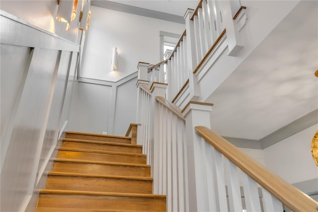 staircase featuring wainscoting and a decorative wall