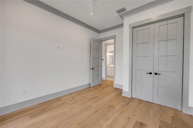 unfurnished bedroom featuring light wood-style floors, baseboards, visible vents, and a closet