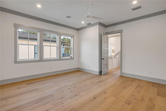 empty room featuring light wood finished floors, baseboards, visible vents, and a ceiling fan