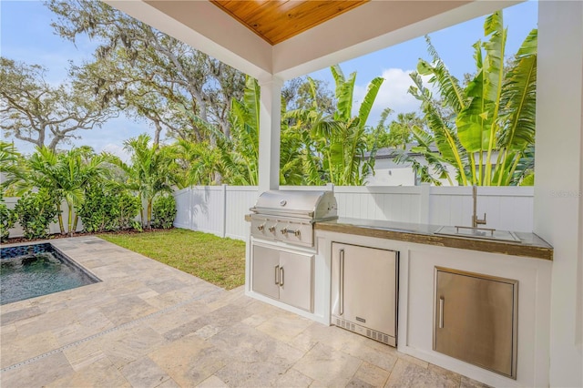 view of patio featuring exterior kitchen, a fenced backyard, and a grill