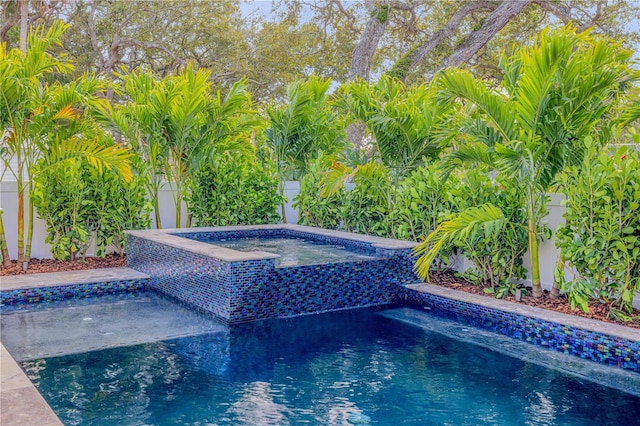 pool with fence private yard and an in ground hot tub