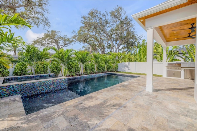 view of pool featuring a fenced in pool, an outdoor kitchen, a patio area, fence, and ceiling fan