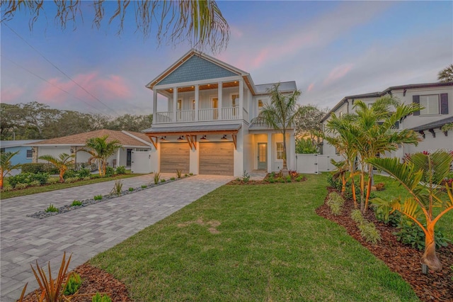 view of front facade with a garage, a balcony, fence, decorative driveway, and a front yard