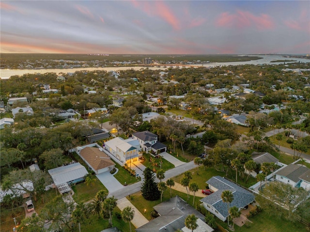 aerial view at dusk with a water view and a residential view