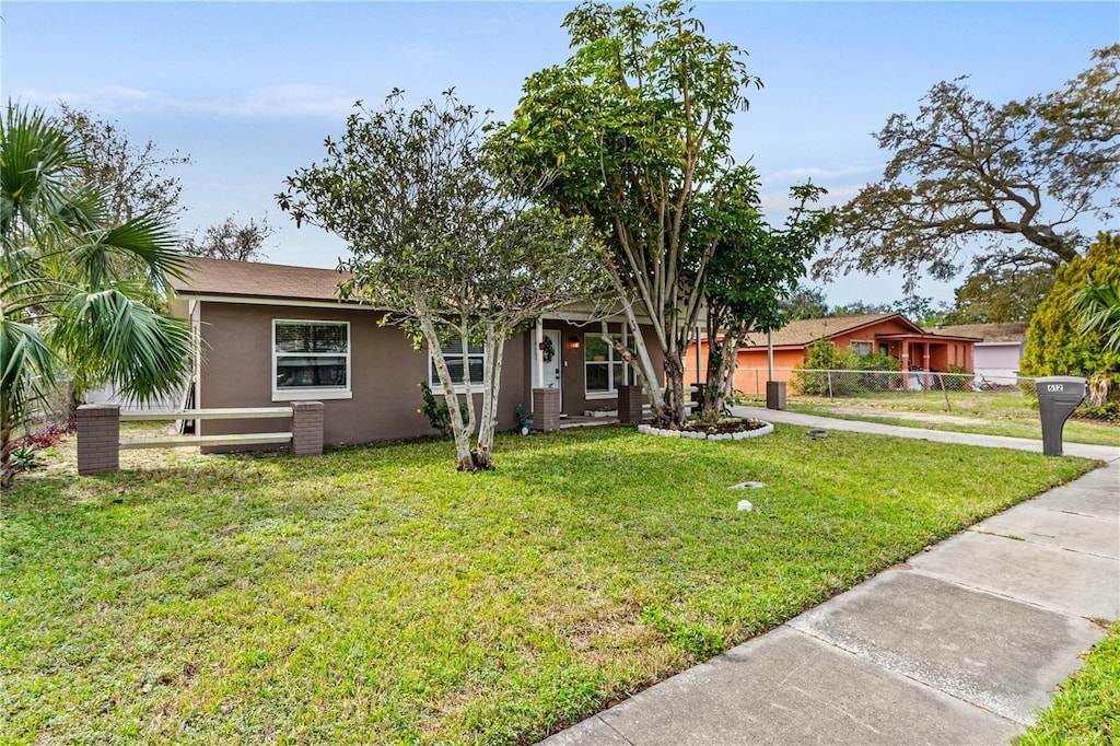 ranch-style house with fence, a front lawn, and stucco siding