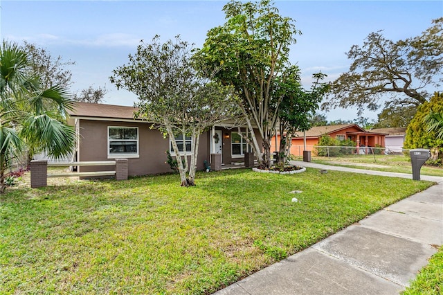 ranch-style house with fence, a front lawn, and stucco siding