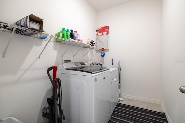 washroom with laundry area, baseboards, washing machine and clothes dryer, and light tile patterned flooring