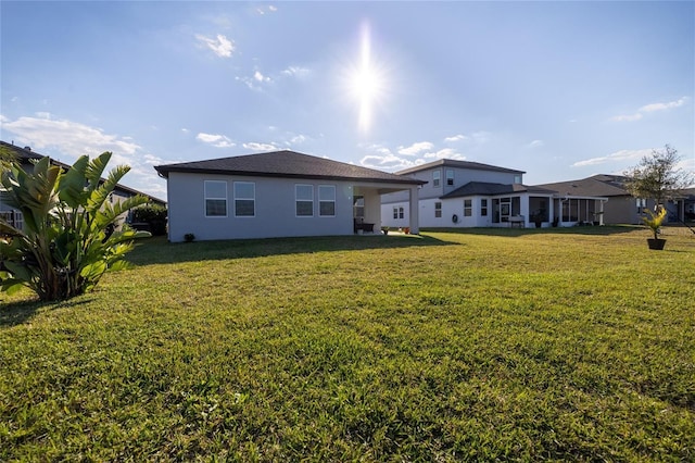 back of property with a lawn and stucco siding