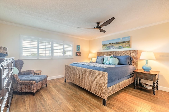 bedroom featuring light wood-style floors, crown molding, a textured ceiling, and baseboards