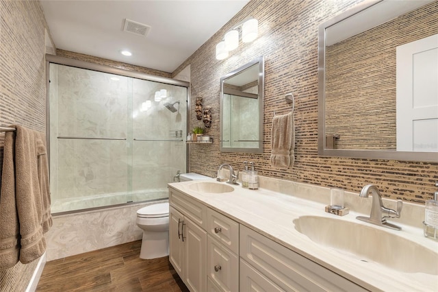 full bathroom with visible vents, a sink, toilet, and combined bath / shower with glass door