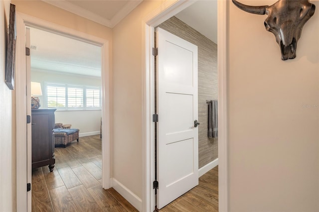 corridor with ornamental molding, baseboards, and wood finished floors