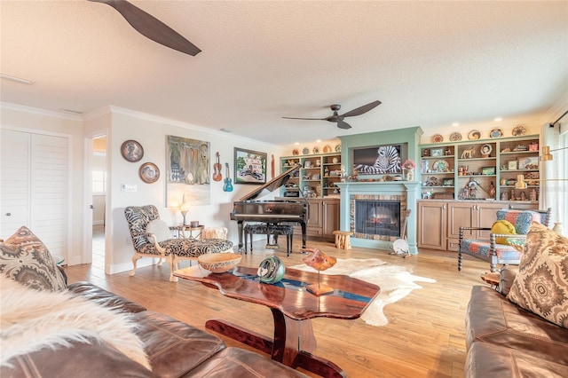 living area featuring light wood-style flooring, ceiling fan, and a textured ceiling