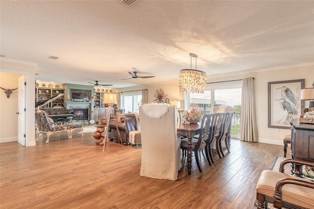 dining area featuring plenty of natural light, crown molding, wood finished floors, and a glass covered fireplace