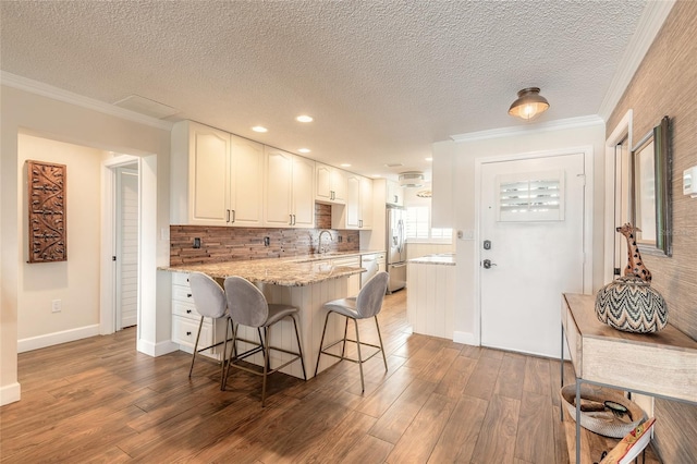 kitchen featuring ornamental molding, a breakfast bar, wood finished floors, and stainless steel fridge with ice dispenser