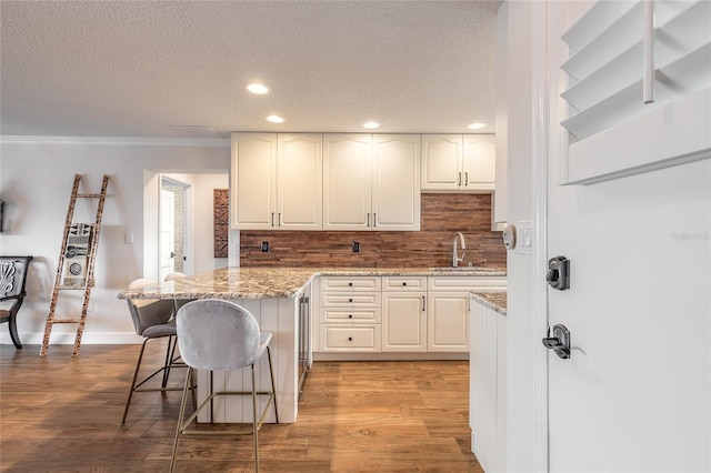 kitchen featuring decorative backsplash, a breakfast bar, a sink, and wood finished floors