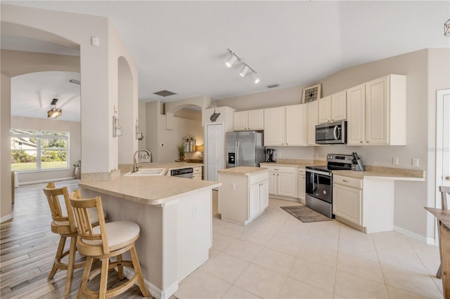 kitchen with stainless steel appliances, light countertops, a sink, a peninsula, and a kitchen breakfast bar