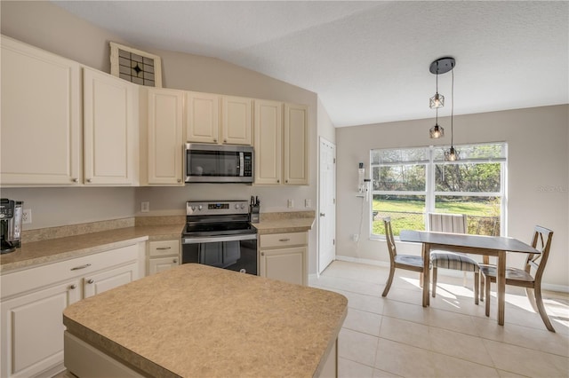 kitchen featuring decorative light fixtures, light tile patterned floors, light countertops, appliances with stainless steel finishes, and vaulted ceiling