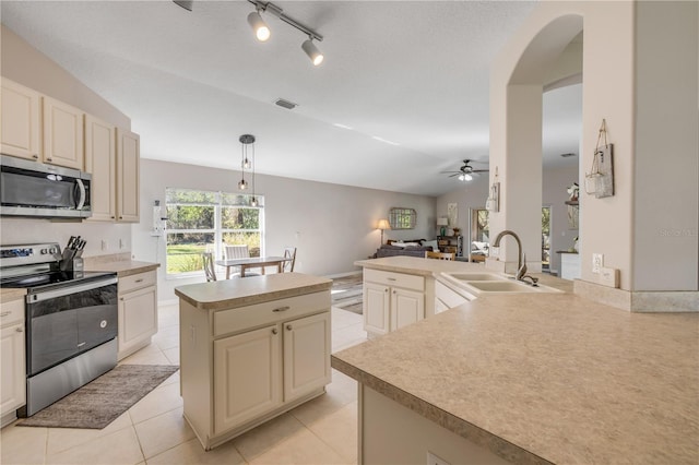 kitchen featuring visible vents, cream cabinets, stainless steel appliances, a sink, and light tile patterned flooring