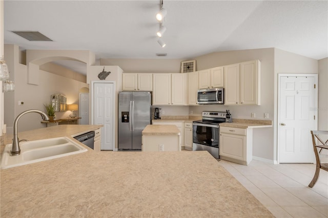 kitchen featuring light tile patterned floors, stainless steel appliances, lofted ceiling, visible vents, and a sink