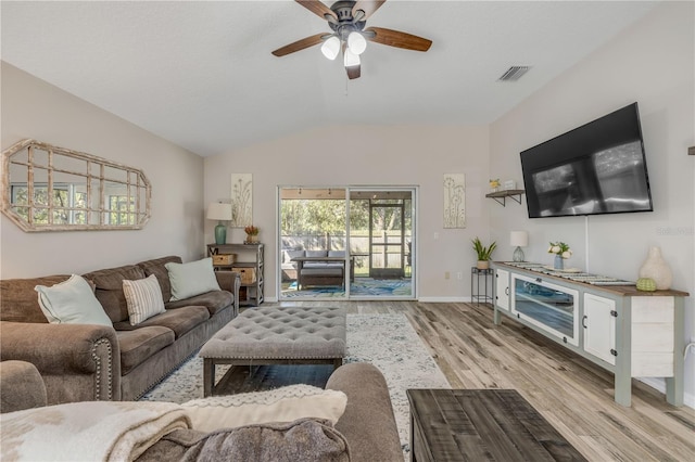 living room featuring a ceiling fan, baseboards, vaulted ceiling, visible vents, and light wood-style floors