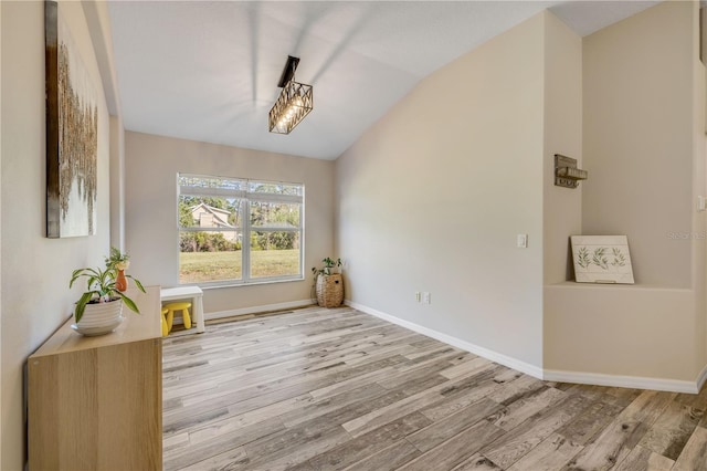 interior space featuring vaulted ceiling, baseboards, and wood finished floors