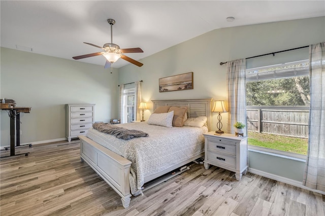 bedroom featuring light wood finished floors, multiple windows, baseboards, and vaulted ceiling