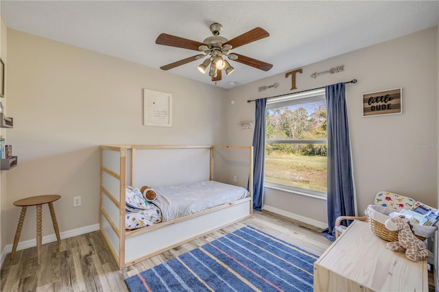 bedroom with ceiling fan, baseboards, and wood finished floors