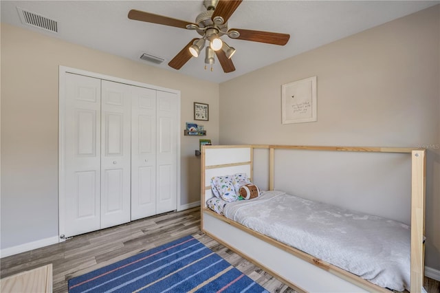 unfurnished bedroom with a closet, visible vents, ceiling fan, and wood finished floors