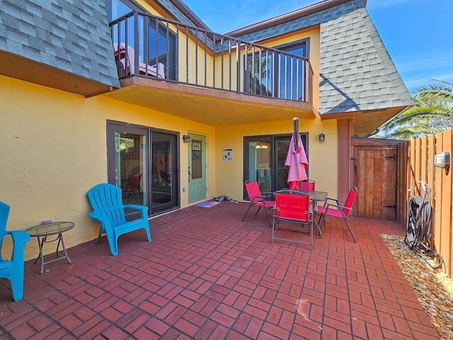 view of patio / terrace featuring a gate, fence, and a balcony